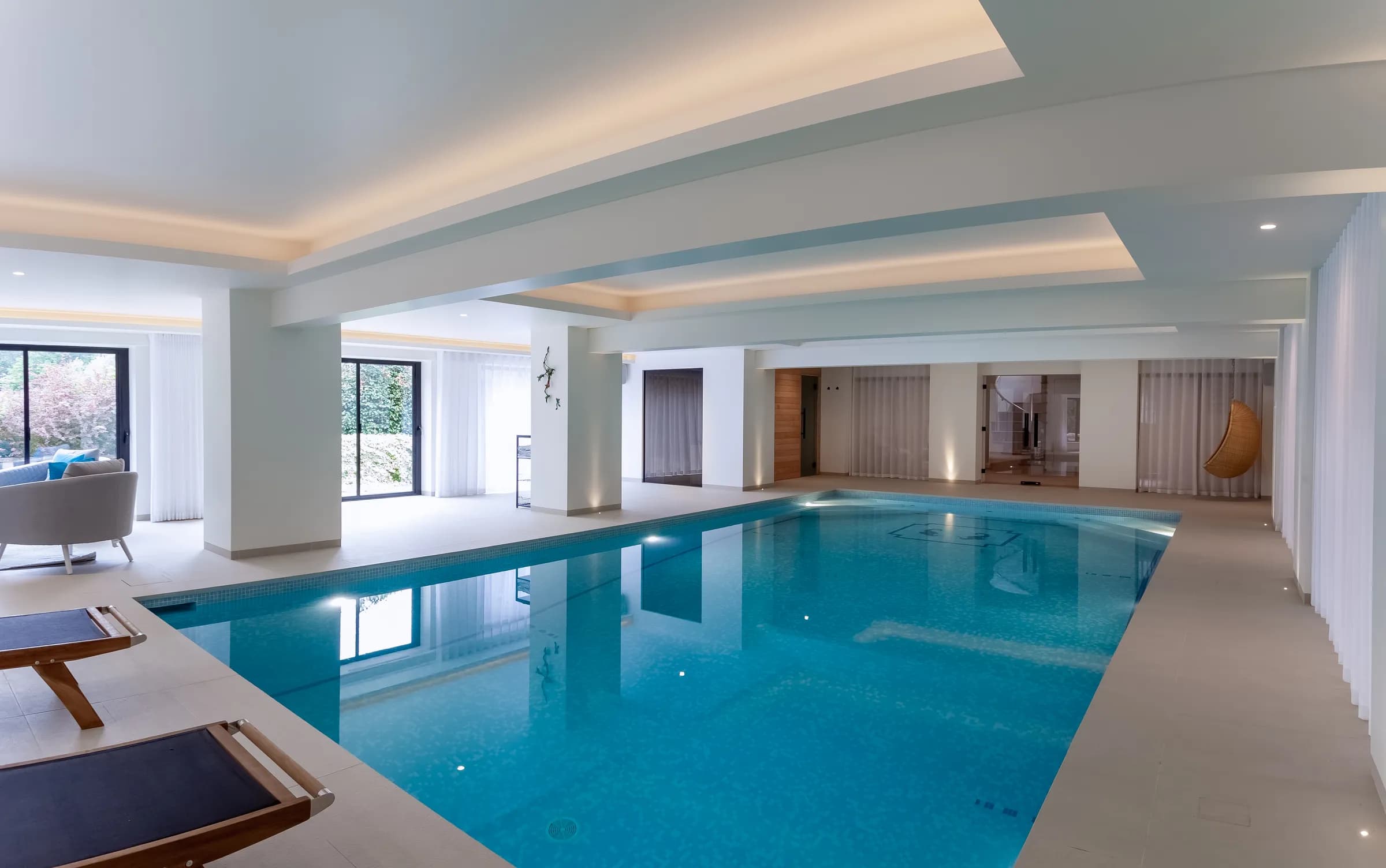 Contemporary indoor swimming pool with glass walls and modern architectural detailing