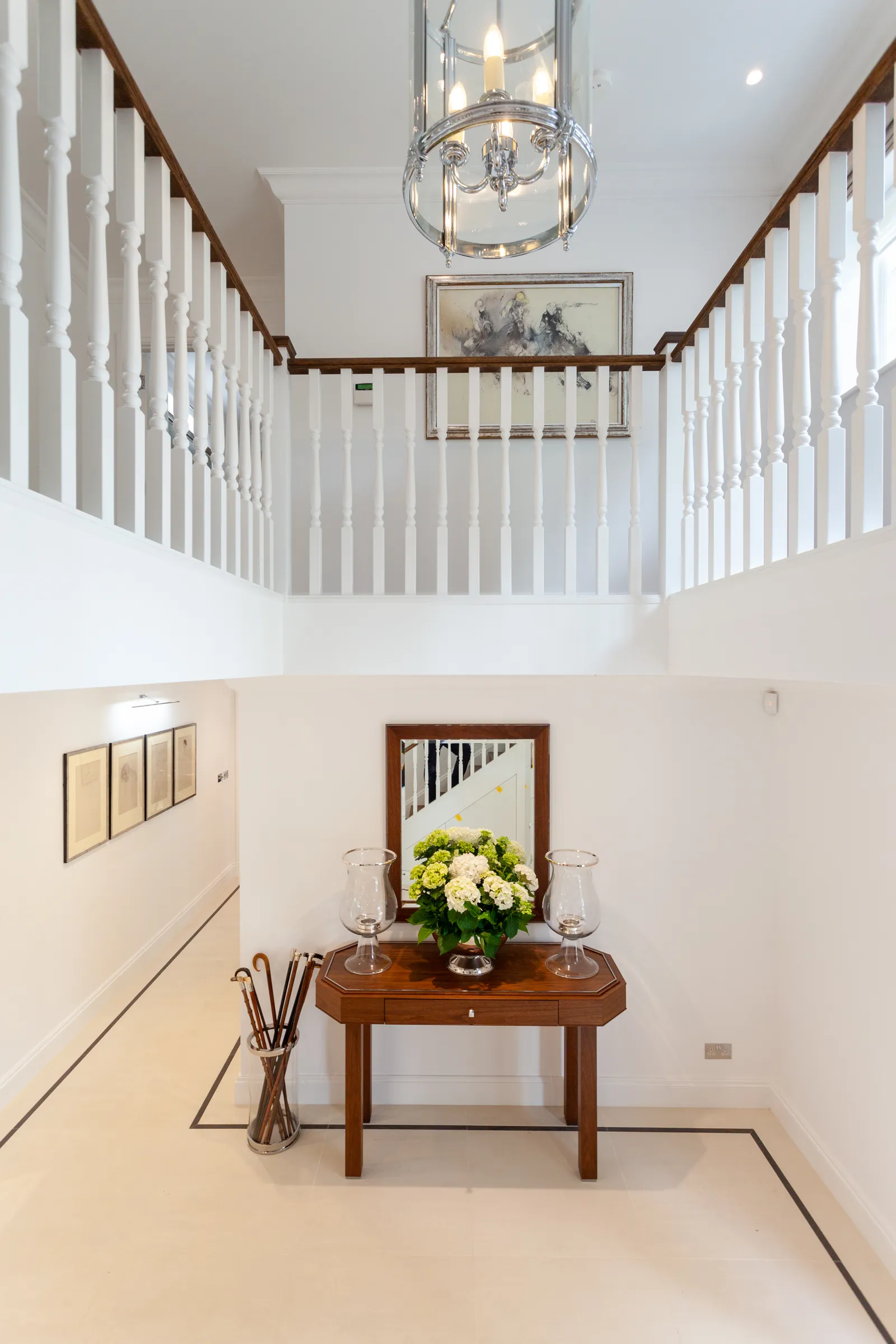 Grand staircase with ornate banister viewed from below, crystal chandelier above